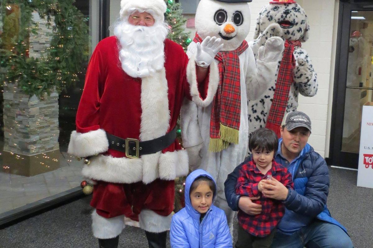 Santa and snowman posing with a family in lobby of Village Hall